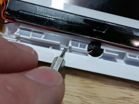 Noting the routing of the black and white wires for later reassembly, remove the microphone and Wi-Fi antenna, carefully pulling the wires through the center of the flex cable so as not to cause any damage.