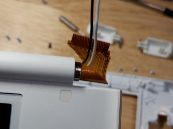 Make sure that both wires are routed through the center of the flex cable and carefully route the flex cable through the slit. The flex cable is incredibly fragile, and it was strengthened in later models. Take your time on this step. If it takes you ten minutes to avoid damaging the flex cable, so be it.