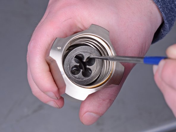 Use a pick tool to remove the metal ball seat from the bottom of the intake valve.