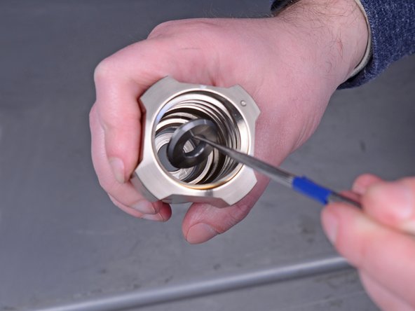 Use a pick tool to remove the ball seat washer from the bottom of the intake valve.
