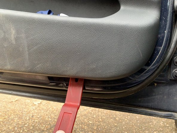 Using your plastic pry tool, pry the door panel loose, beginning along the bottom edge and moving up each side.