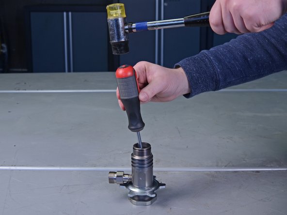 Flip the pump cylinder upside down and use a flathead screwdriver and mallet to gently tap the throat packing O-rings, loosening them from the cylinder.