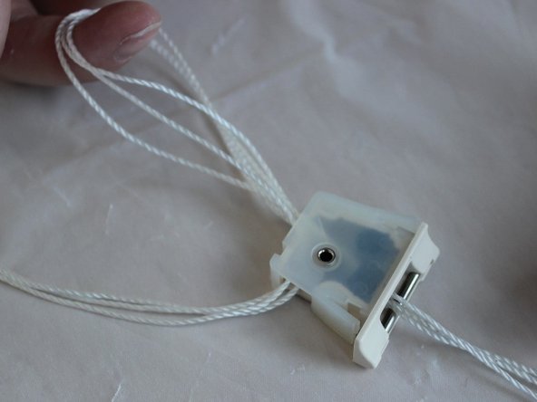 Thread them back through the back opening and out of the front opening. Make sure to pass the strings through the black rectangular piece inside the cord lock.