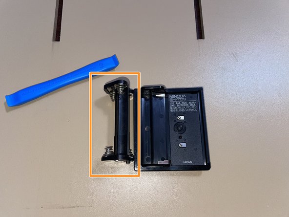 (AAA) Cleaning battery leakage (Maxxum 5000/7000), Remove the battery retention clip: crwdns2935265:04crwdnd2935265:03crwdnd2935265:03crwdne2935265:0