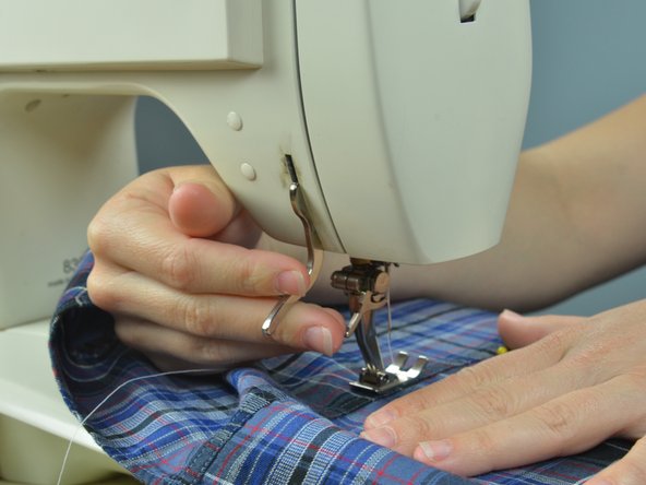 Put the garment in the machine, starting a few inches before the torn seam to overlap with the stitches.