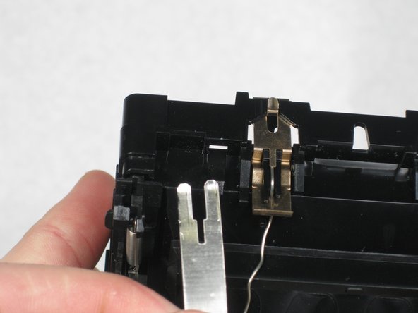 Unhook the wire on the left of the brass tab.