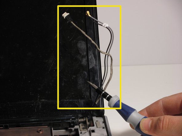 Remove the WLAN antenna cables and the webcam/ microphone cable from the clips built into the top cover.