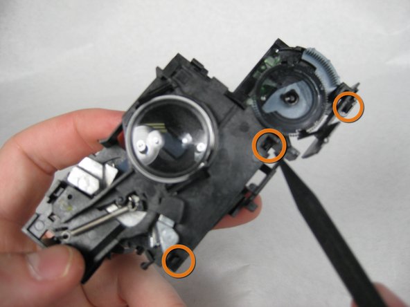 CAUTION: The lens may pop out when the tab is released.