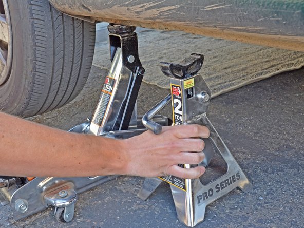 Use the handle on the jack stand to lower it and remove the jack stand from underneath the car.