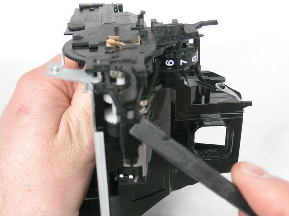 The first is directly under the spring mounted at the back left of the camera