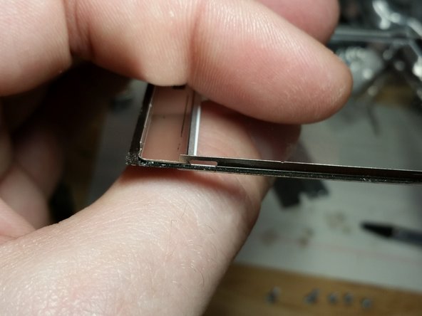 The plastic cover is wedged underneath the back metal cover and is held on by a  few different schemes, depending upon how old the DS Lite is. One method is two tabs on each side. Gently work the tabs loose without removing the back metal cover. This step is unnecessary unless you're changing the color of the shell.