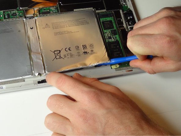 The battery is attached to the device by strong adhesive tape. Use a plastic opening tool to pry around the underside of the battery.