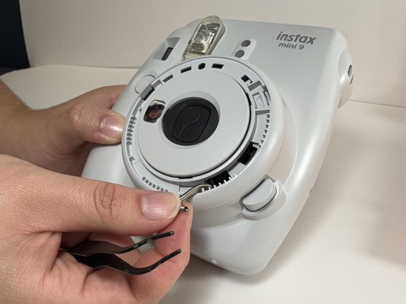 Fujifilm Instax Mini 9 Flash Capacitor Replacement, Unhook Lens Spring: crwdns2935265:07crwdnd2935265:02crwdnd2935265:02crwdne2935265:0