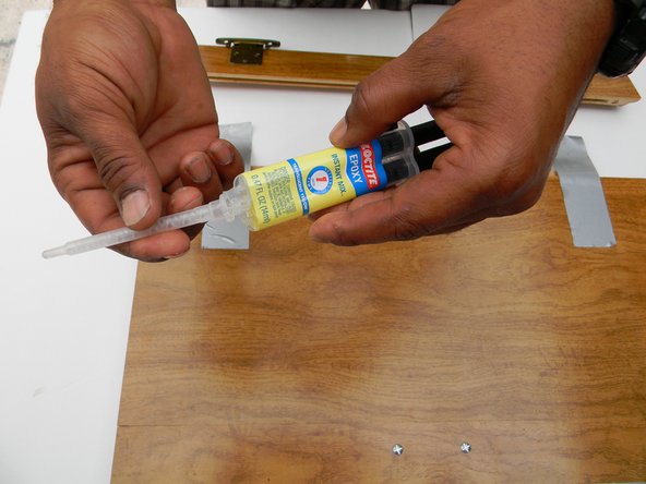 This is a 5 minute  quick setting 2 part wood epoxy. Take the top off the epoxy.  Connect the syringe tip and lock it in place. Press the plunger so you can fill the needle tip with epoxy.