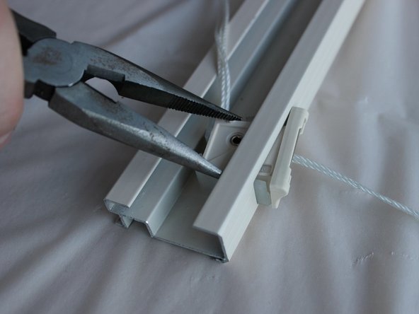 Using the needle nose pliers, push the cord lock clips in from the side and slide the cord lock out, removing the strings and setting the cord lock aside.