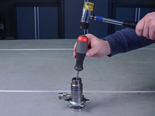 Flip the pump cylinder upside down and use a flathead screwdriver and mallet to gently tap the throat packing O-rings, loosening them from the cylinder.