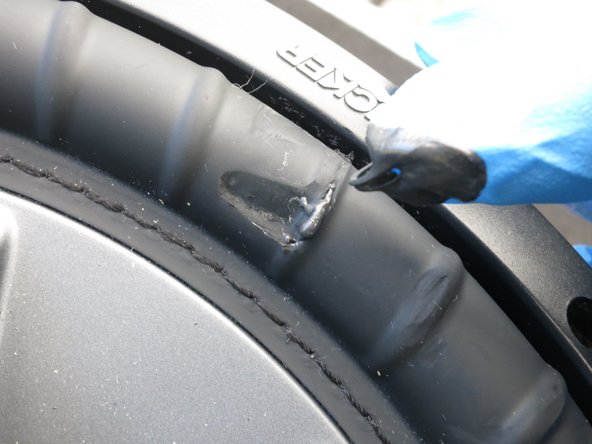 Gently spread the RTV silicone across the front of the torn subwoofer surround.
