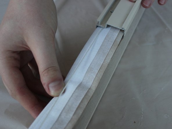 Slide the top rail onto the shade, pulling the strings tight through the cord lock.